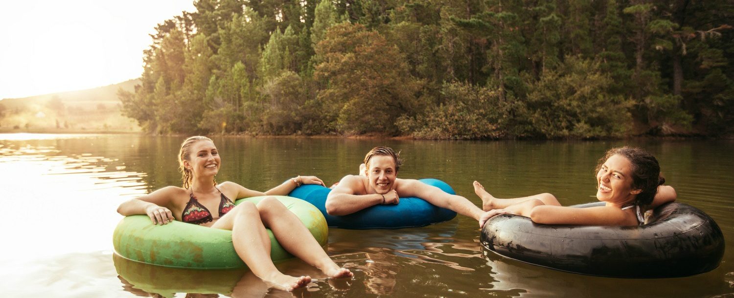 Two women and a man tubing on a river